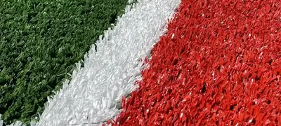 Detaliu de gazon sintetic multisport, verde cu zonă roșie și linie albă de marcaj